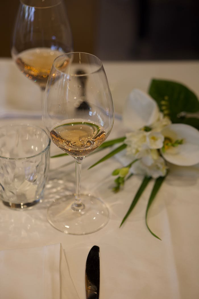 A refined dining setup with a wine glass, floral arrangement, and silverware.