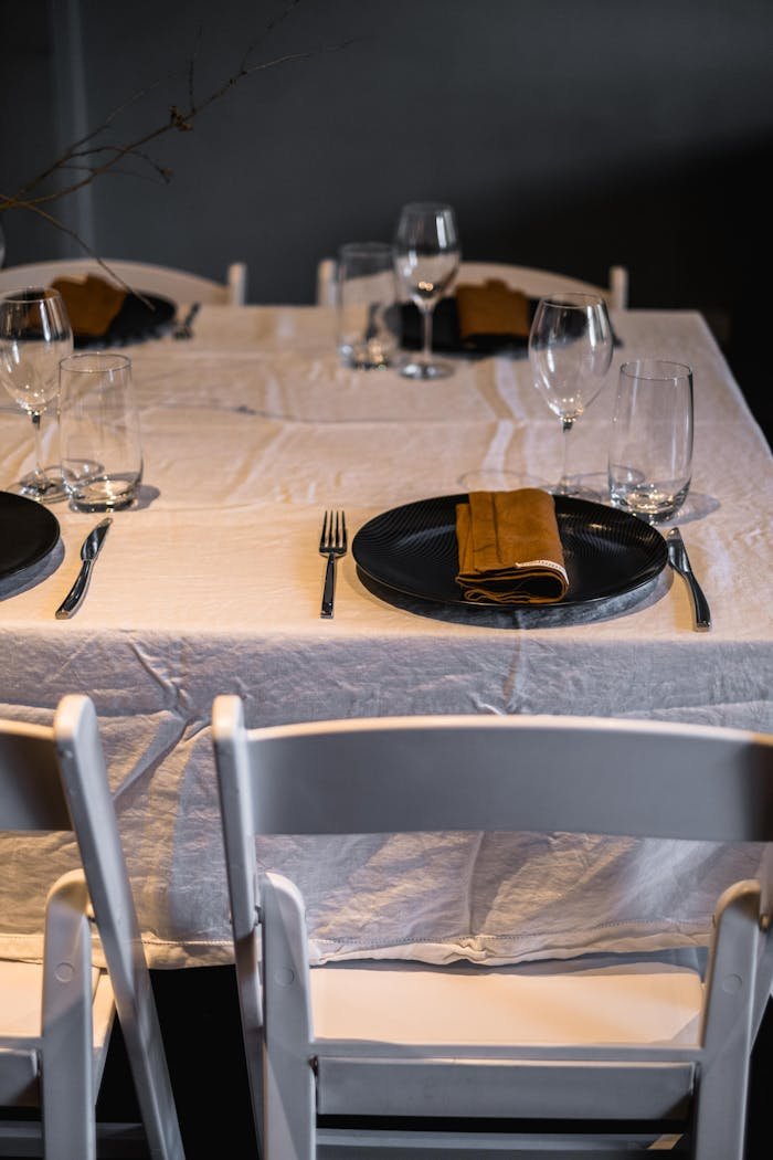 A sophisticated table setting featuring glassware, dinnerware, and a white tablecloth, perfect for formal dining.